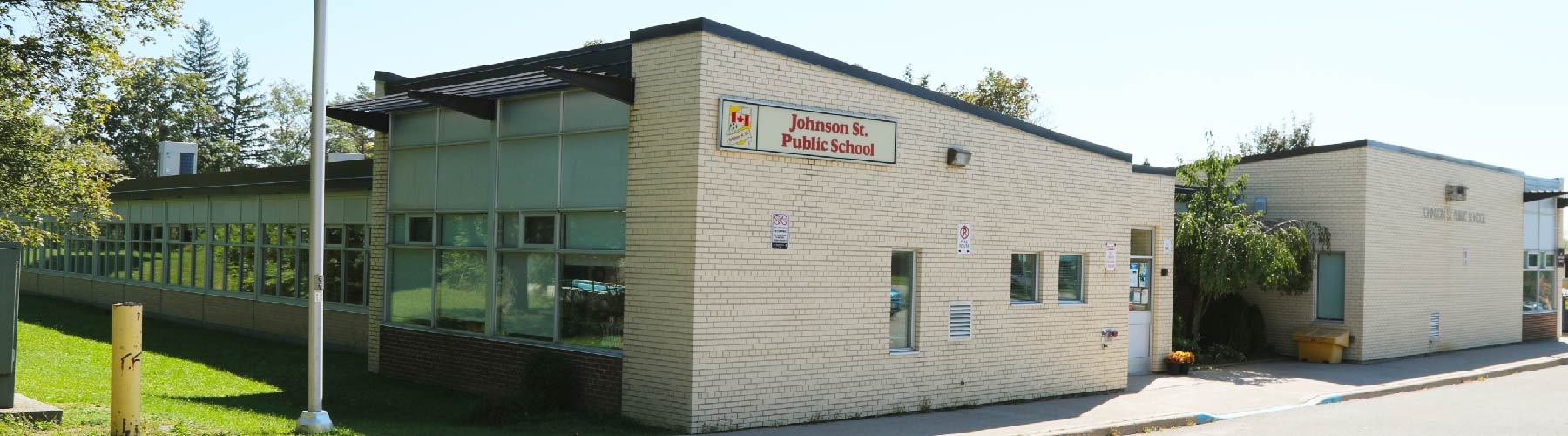 Johnson Street Public School in Barrie — a single-storey beige brick school building with its entrance sign and a long row of classroom windows